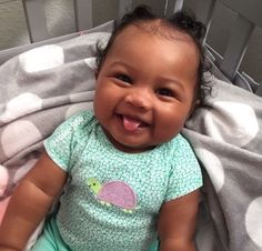 a smiling baby sitting on top of a bed