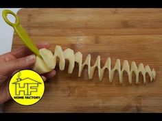 someone is cutting up some food on a wooden board with a yellow handled scissor