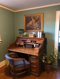 a wooden desk sitting in the corner of a room next to a chair and potted plant