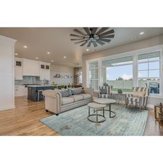 a living room filled with furniture next to a kitchen and an open concept floor plan