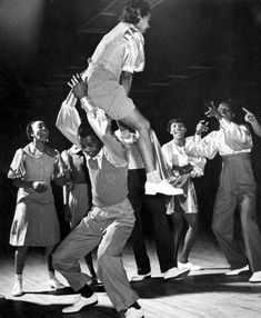 a group of people standing on top of each other in front of a person jumping up into the air