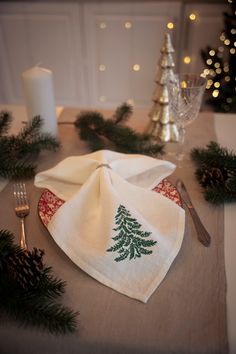 a napkin with a christmas tree on it sitting on top of a table next to a candle