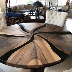 a round wooden table with white chairs around it in a living room filled with furniture