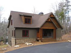 a house in the middle of a wooded area with rocks on the ground and trees around it