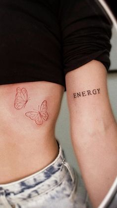 a woman's stomach with two butterflies and the word energy tattooed on her side