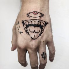 a person's hand with an evil face and eye tattoo on the middle of it