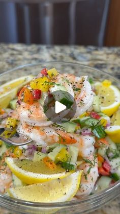 a glass bowl filled with shrimp and lemon slices