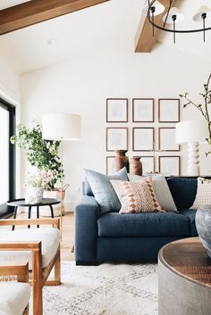 a living room with blue couches and pictures on the wall behind them in frames