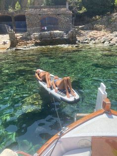 two people laying on a small boat in the water