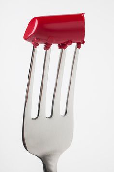 a fork that has some red plastic on it's head and two forks sticking out of it