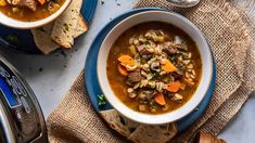 two bowls of soup with bread on the side