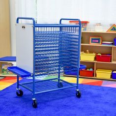 a blue shopping cart sitting on top of a carpeted floor next to a book shelf