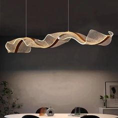 a dining room with a table, chairs and lights hanging from it's ceiling