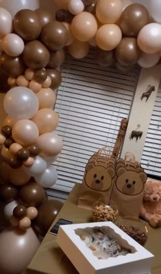 a table topped with balloons and stuffed animals on it's sides next to a window