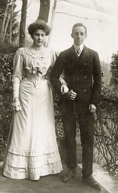 an old black and white photo of a man and woman standing next to each other