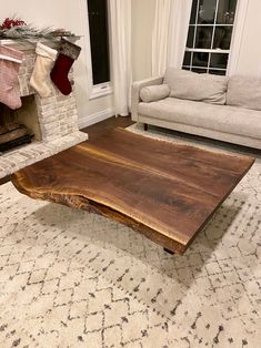 a wooden table sitting on top of a rug in front of a couch and fireplace