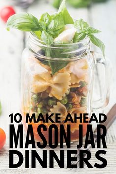 a mason jar filled with pasta and basil on top of a table next to tomatoes