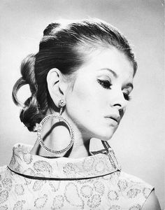 a black and white photo of a woman with large earrings