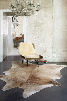 a living room area with a chair, rug and chandelier hanging from the ceiling