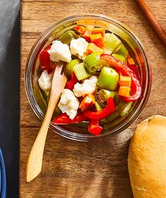 a glass bowl filled with vegetables next to bread