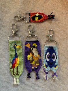 three keychains with cartoon characters on them sitting on a white cloth covered surface