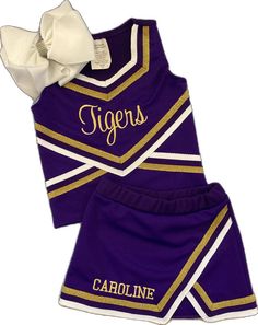 a purple and gold cheer uniform with a white bow on the side, sitting next to it