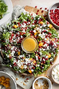 a platter filled with salad and dressing on top of a wooden cutting board next to other dishes