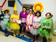 several women dressed in costumes posing for a photo with one holding a book and the other wearing a hat