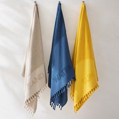 three towels are hanging on the wall next to each other, one blue and one yellow