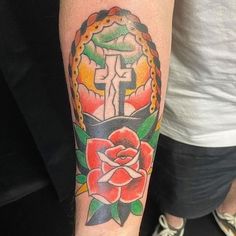 a person with a cross and rose tattoo on their arm