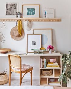 a white desk topped with lots of shelves filled with pictures and other items next to a potted plant