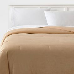 a bed with white pillows and tan sheets