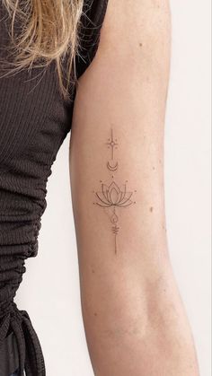 a woman's arm with a cross and lotus tattoo on the back of her left arm