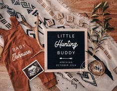 the baby announcement is displayed next to an orange bib and other items on a blanket