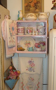 an old fashioned china cabinet in the corner of a room with dishes and other items on it