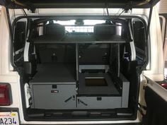 the back end of a white van with its doors open and two seats folded down