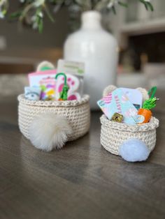 two small baskets filled with toys on top of a wooden table next to a vase