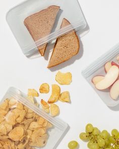 three plastic containers filled with different types of snacks and fruit on top of a white surface