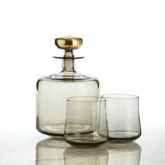 two glasses and a decanter are sitting on a table with a white background