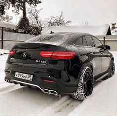 a black car parked on the side of a snow covered road