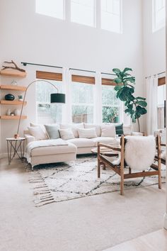 a living room filled with lots of furniture next to a large window on top of a white rug