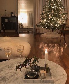 a living room with a christmas tree in the corner and wine glasses on the coffee table