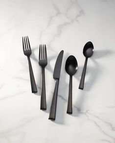 five forks, two spoons and one knife on a marble table top with white background