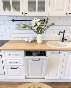 a kitchen with white cabinets and wood flooring has a basket on the counter next to the dishwasher