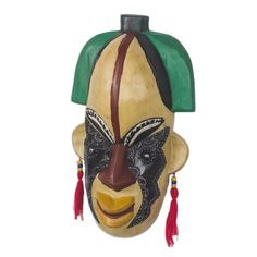 an african mask with green and brown colors on it's face, hanging from the side