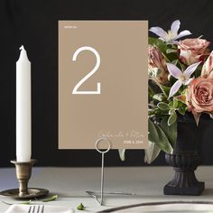 a table with flowers and a candle on it, next to a sign that says 2