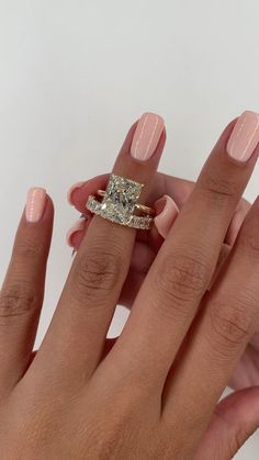 a woman's hand with a diamond ring on her finger and the other hand holding an engagement ring