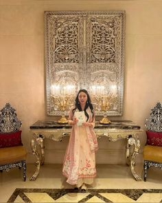 a woman standing in front of a table with chairs and a mirror on the wall