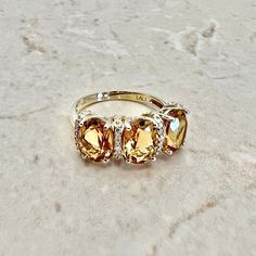 Beautiful 14 karat yellow gold cocktail ring featuring 3 natural oval citrines. The gemstones weigh approximately 3.6 carats, and are accented by 20 diamonds weighing approximately 0.08 CTTW. Citrine is the birthstone for November! Weighs 3.3 grams. Size 7 US / N 1/2 - O UK. > Resizing included. This ring can be resized to fit most fingers. Please contact us for details. Resized rings are final sale. Free resizing does not apply to discounted rings over 15% off. Birthstone: November/April. Condi Yellow Oval Topaz Ring In 14k Gold, Oval Citrine Birthstone Ring, Oval Yellow Citrine Birthstone Ring, Elegant Yellow Oval Birthstone Ring, Oval Topaz Birthstone Ring In Yellow Gold, Yellow Oval Birthstone Anniversary Ring, Oval Yellow Birthstone Anniversary Ring, Oval Yellow Gold Birthstone Anniversary Ring, Oval Citrine Birthstone Ring For Anniversary