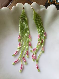 Brick stitch earrings with extra long fringe, green seed beads and pink E beads. Green Dangle Chandelier Earrings For Summer, Green Beaded Fringe Jewelry For Summer, Green Beaded Fringe Earrings With Round Beads, Summer Green Dangle Chandelier Earrings, Green Beaded Earrings With Round Beads And Fringe, Spring Fringe Dangle Earrings, Green Beaded Earrings With Fringe For Summer, Green Fringe Earrings For Summer, Green Beaded Earrings With Fringe